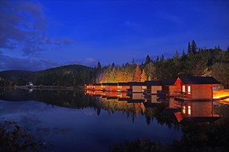Small wooden holiday cabins at dusk on the shore of a lake