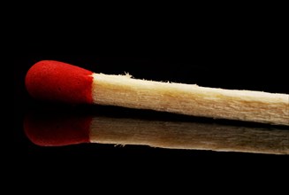 Single matchstick with reflection over black background
