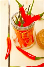 Red chili peppers on a glass jar over white wood rustic table