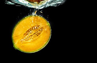 Half of Orange cantaloupe melon sinking and isolated on black background