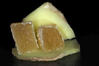 Two cubed candied ginger lies on a slice of fresh ginger