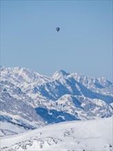 Hot air balloons flying over snow-covered Alpine peaks