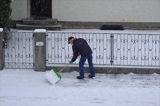 Man clearing snow from the pavement