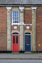 Doors of two Victorian red brick houses next to each other