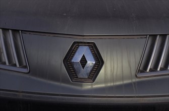 Renault car logo on dirty front panel with radiator grille