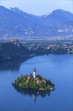 The island of Bled with its church on Lake Bled surrounded by the Julian Alps in Lake Bled