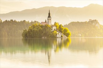Placid scene of the island of Bled with its church surrounded by the Julian Alps