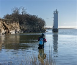 Angler standing in the water at the lighthouse of Maltzien on the island of Ruegen