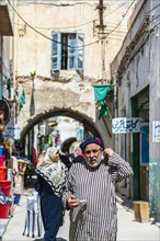 An elderly man in traditional attire walking through the streets of the old town of Tripoli