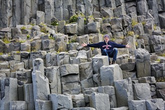 Tourist sitting on basalt columns in summer