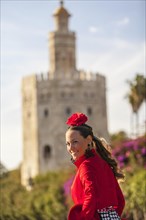 A beautiful young woman in front of the Torre del Oro on her way to the Feria de Abril in Seville