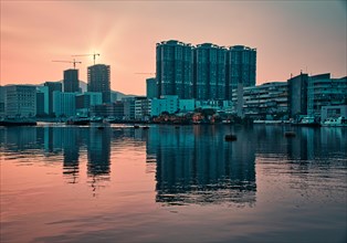 Tall buildings by the sea with reflections at sunset in Macau
