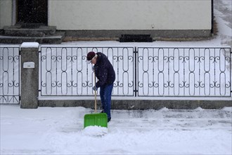 Man clearing snow from the pavement