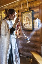 A Russian Orthodox priest in a traditional wooden church during the ceremony
