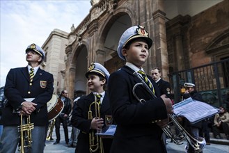 Young and older members of the band during a break from playing marches during Good Friday in the streets of Trapani