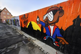 Narrow alley with graffiti on board fence