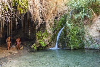 Two young women in one of the caves with a stream dating back to biblical times in the Negev desert in the Nature Reserve of Ein Gedi