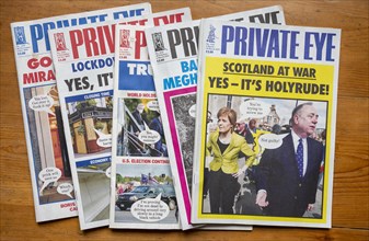Front covers of editions of Private Eye satirical magazines viewed from above