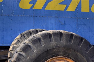 Tyres from tractor in front of blue metal from scrap car