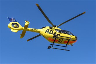 ADAC rescue helicopter Christoph 40 from Augsburg Hospital taking off against a blue sky