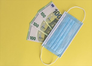 Medical masks and Euro banknotes. Financial crisis due to Coronavirus losses