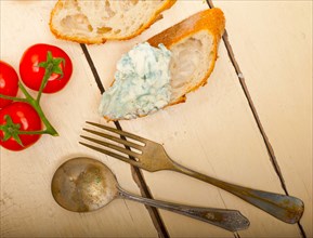 Fresh blue cheese spread ove french baguette with cherry tomatoes on side