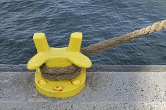 Rope and yellow mooring bollard in seaport