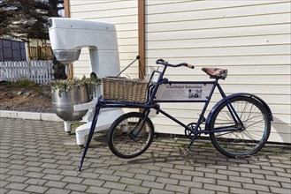 Cargo bike with basket and large food processor as decoration in front of a bakery