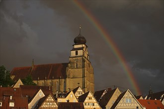 Stormy atmosphere with rainbow over collegiate church and old town