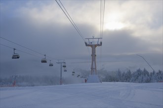 Chairlift in ski area and sun in winter