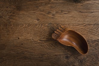 Wooden bowl in the shape of a foot on a wooden table