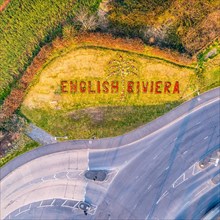 Top Down view of inscription on the flower bed with flowers Welcome in English Riviera from a drone