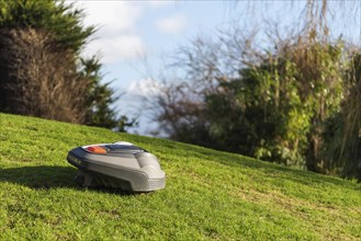 The robotic lawnmower mows the lawn on the slope