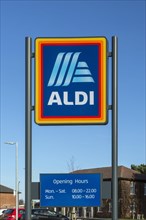 Aldi shop sign with opening hours against blue sky