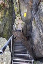 Hiking trail over stairs through narrow gorges between the rocks