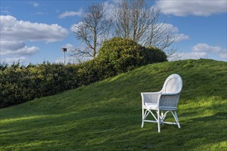 A white chair on a green lawn under a hill