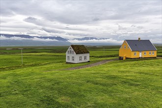 Grass sod house and yellow wooden house in a meadow