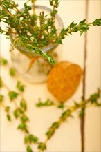 Fresh thyme on a glass jar over a white wood rustic table