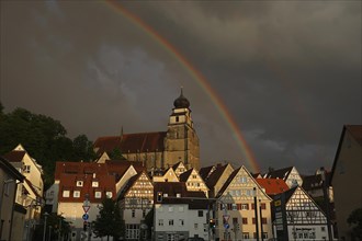 Stormy atmosphere with rainbow over collegiate church and old town
