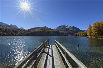 Wooden jetty on lake with sun in autumn