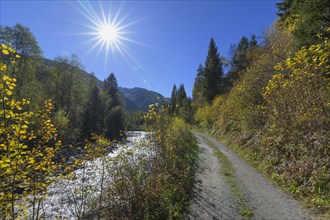 Dirt road on the river with sun in autumn