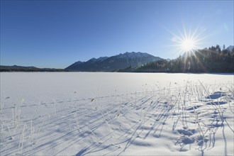 Frozen lake Barmsee with Karwendel mountainrange on morning with sun in winter