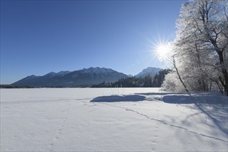Frozen lake Barmsee with Karwendel mountainrange on morning with sun in winter