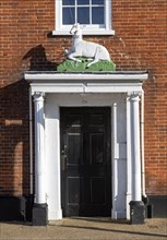 Historic sculpture of white hart deer above former entrance door to hotel