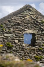Decaying gable end and window of former village house on Great Blasket Island with view of Blasket Sound. County Kerry