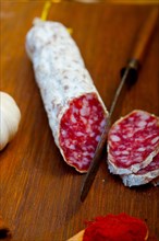 Traditional Italian salame cured sausage sliced on a wood board