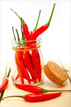 Red chili peppers on a glass jar over white wood rustic table