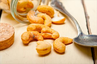 Cashew nuts on a glass jar over white rustic wood table