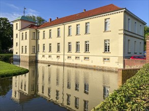 View of classicist castle Westerholt with reflection of building in historical moat