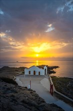 Small white Greek church by the sea at sunrise. Beautiful landscape shot with view to the horizon